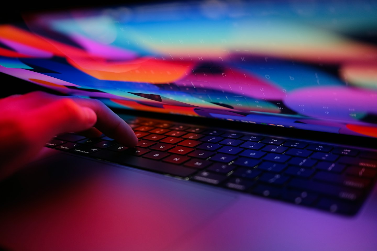 Dłonie piszące na klawiaturze laptopa z abstrakcyjną grafiką cyfrową.